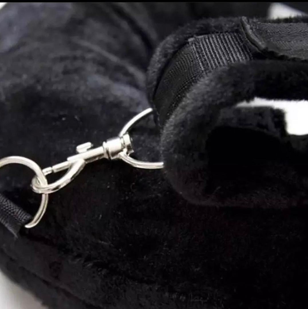 Close-up of a gloved hand holding a silver carabiner clip attached to black fabric straps