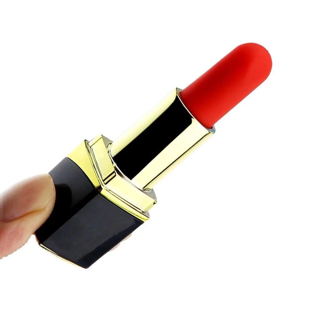 Hand holding a red lipstick-style vibrator with a black and gold case