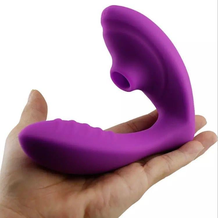 Purple curved intimate wellness device held in a person's hand against a white background