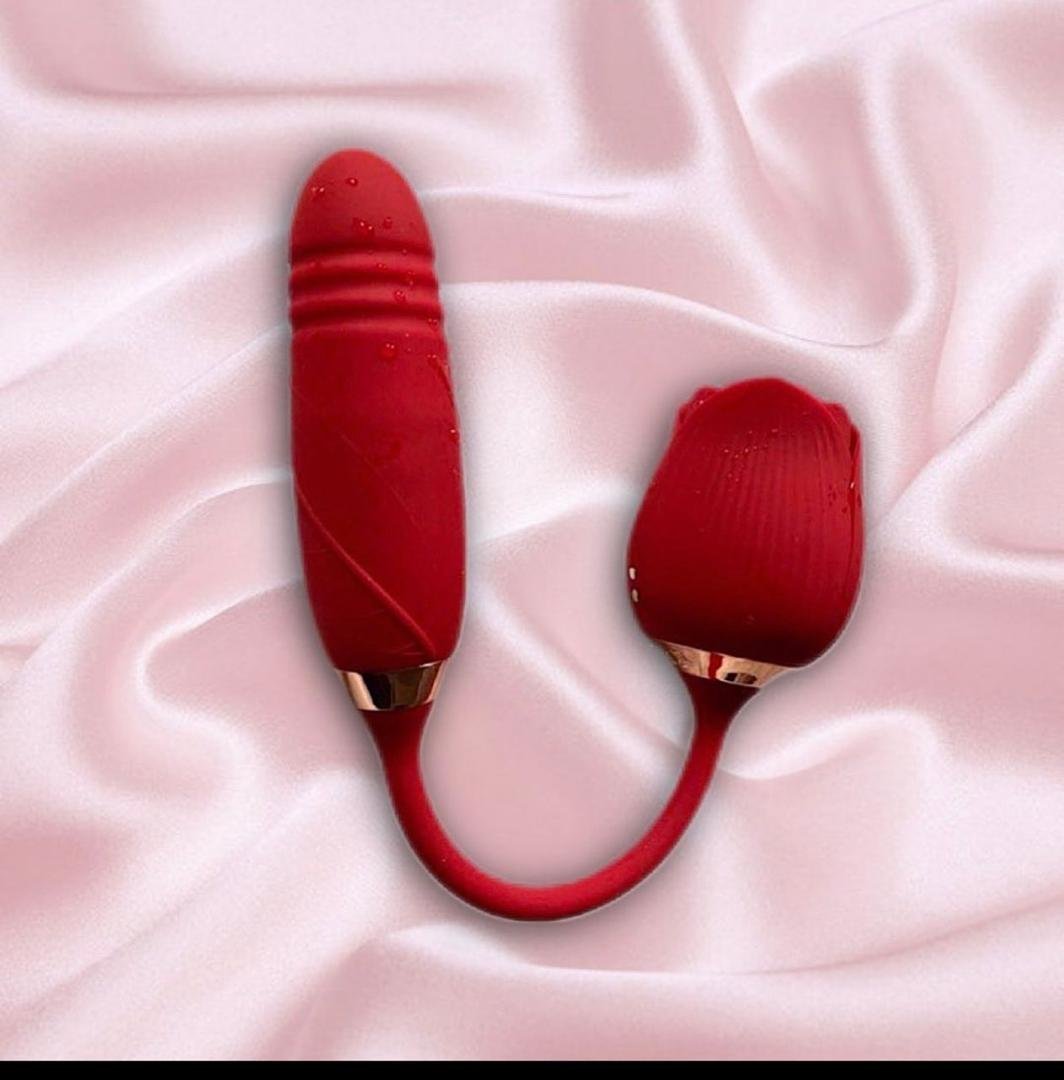 Red dual-ended intimate wellness device with gold accents laid on pink silky fabric