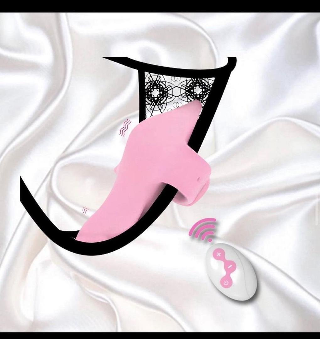 Pink wearable vibrator with black harness and wireless remote control on white satin background