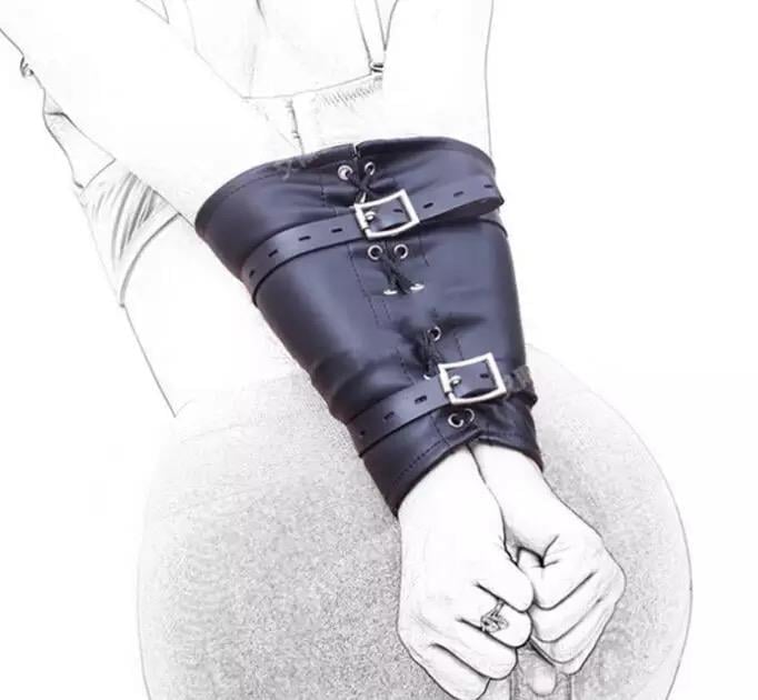 Person wearing a black leather arm cuff with buckles and straps, hands clasped together in front of white clothing
